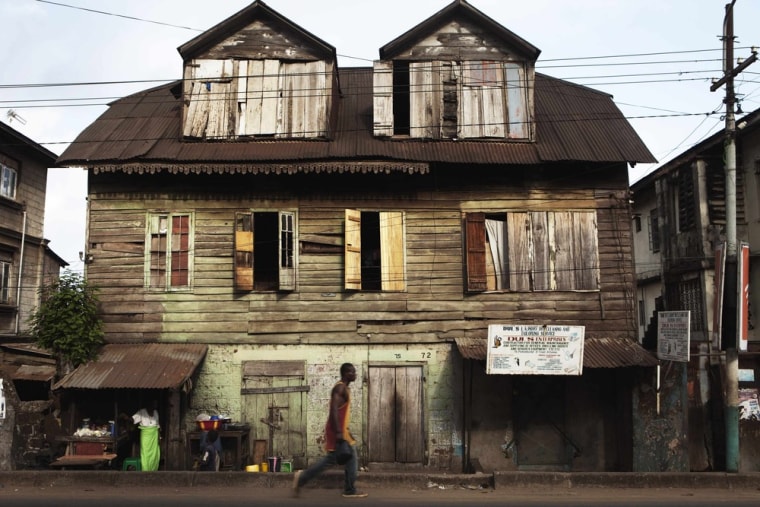 A pedestrian walks past a traditional colonial-era Board House dating back about a century on Pademba Road in Sierra Leone's capital Freetown on April 27. Scattered across Sierra Leone's capital Freetown stand ageing wooden houses, some of which look more like they belong on the east coast of 18th century America than in a steamy west African city. Others look like they may have been built hundreds of years ago in the islands of the Caribbean, another reflection of Sierra Leone's history as a colony established for freed slaves.