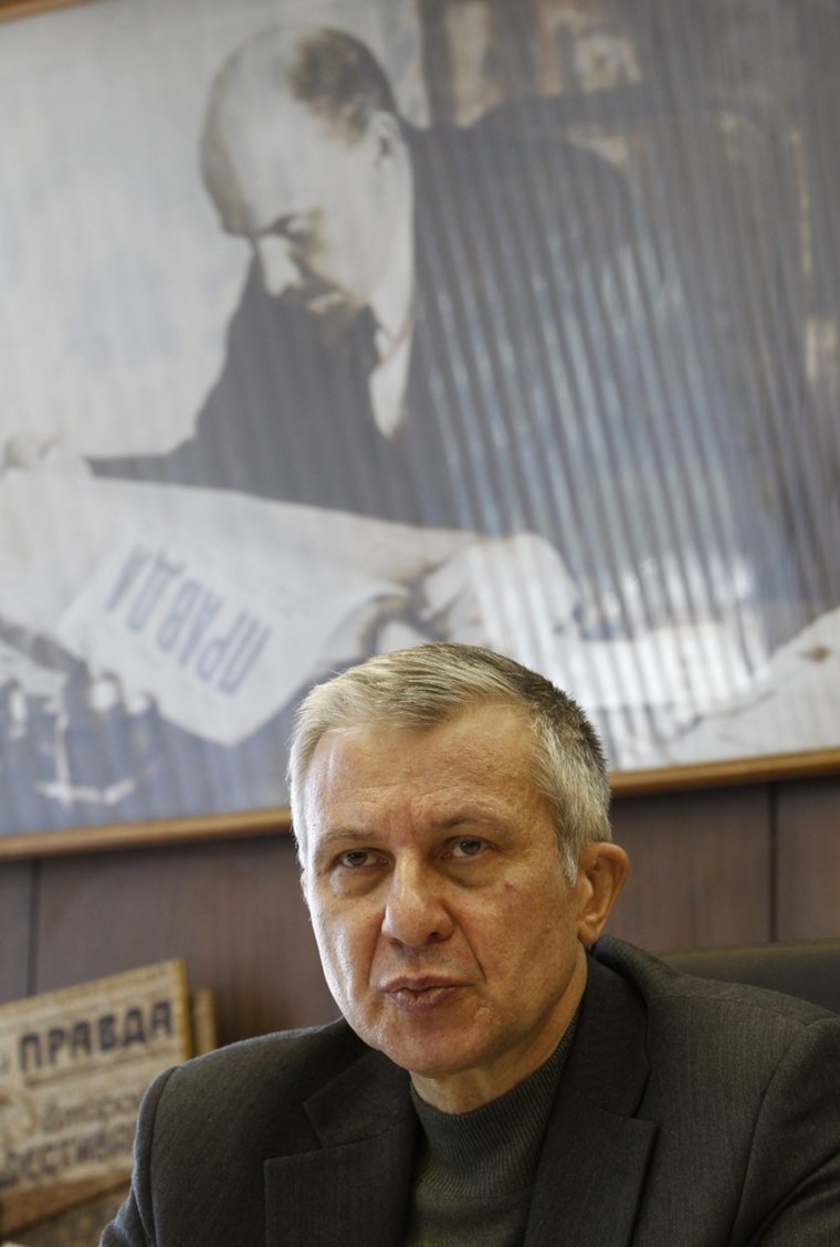 Boris Komotsky, editor of Pravda newspaper, works at his desk in an office, with an image of Soviet state founder Vladimir Lenin seen in the background, at Moscow.