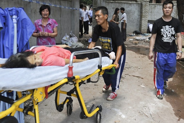 Xian, center, the husband of Li Jie'e, accompanied by his son Xiyong, right, pushes his wife's body on a transport stretcher as another relative, left, burns incense in Yangji village on May 10, 2012.