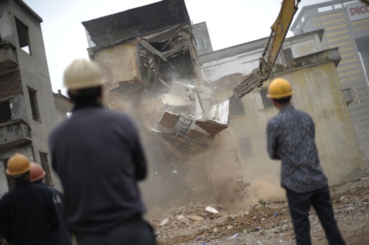 Demolition workers look at a building being taken down in Yangji village on March 21, 2012, the same day that Li Jie'e's home was reportedly destroyed.