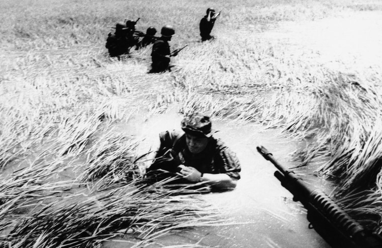 In this May 11, 1965 file photo, Associated Press photographer Horst Faas tries to get back on a U.S. helicopter after a day out with Vietnamese rangers in a flooded plain of reeds.