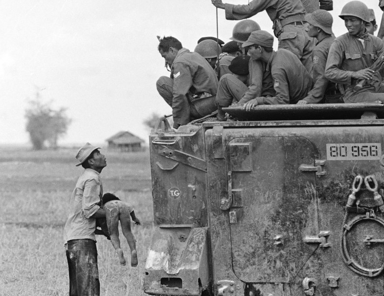 A father holds the body of his child as South Vietnamese Army Rangers look down from their armored vehicle. The child was killed as government forces pursued guerrillas into a village near the Cambodian border. This image is one of several shot by Associated Press photographer Horst Faas which earned him the first of two Pulitzer Prizes,