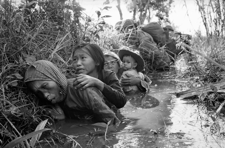 Women and children crouch in a muddy canal as they take cover from intense Viet Cong fire at Bao Trai, about 20 miles west of Saigon, Vietnam, in January 1966.