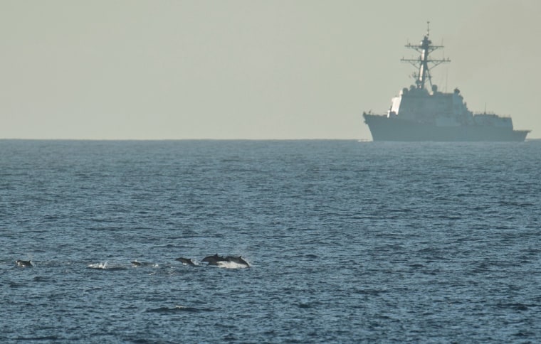 Dolphins surface as the USS Halsey destroyer maneuvers off Southern California on Sept. 30, 2011.