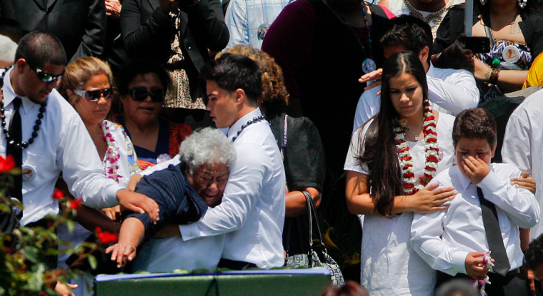 Luisa Seau, third from fron left, mother of former football player Junior Seau who committed suicide last week, is held by her grandson as she reaches for the casket of her deceased son as it is lowered into the ground at his burial on Friday in Oceanside, Calif. Junior's three other children, right, look on.