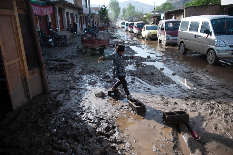 A young girl makes her way along a mud-covered street after a storm hit the village of Minxian, China. Forty people were killed when a brief but violent hailstorm and torrential rain swept through a mountainous region of northwest China.