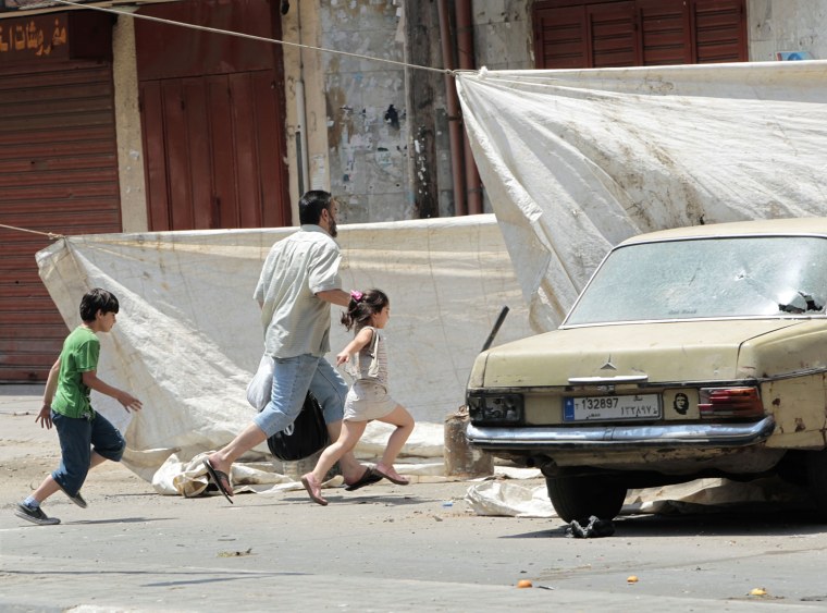 A Lebanese Sunni family run between white tarps hung to provide cover from snipers as they flee their house during clashes, in the northern port city of Tripoli, Lebanon, on May 14.