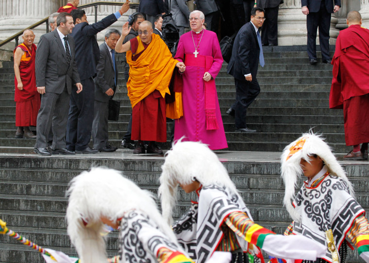 Dalai Lama, Tibetan Buddhist spiritual leader, center left, with St. Paul's Cathedral Canon Pastor Reverend Michael Colclough, center right, waves as he arrives at St. Paul's Cathedral in London to receive the 2012 Templeton Prize awarded to him for encouraging scientific research and harmony among religions, on May 14.