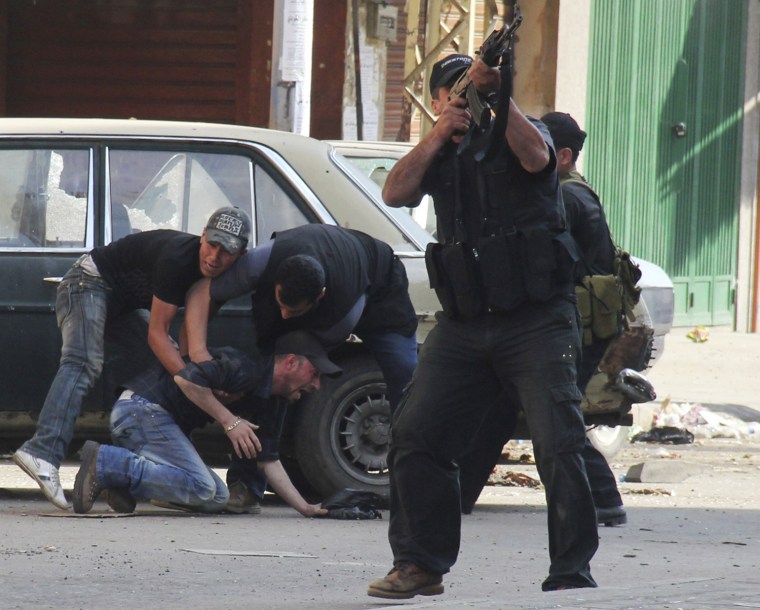 A Sunni Muslim gunman fires his rifle as others help an injured colleague during clashes at the Sunni Muslim Bab al-Tebbaneh neighborhood in Tripoli, northern Lebanon, on May 14. Two men were killed and at least 20 people were wounded in clashes between Alawite supporters of Syrian President Bashar al-Assad and Sunni Muslims in the Lebanese city of Tripoli, medical sources said on Monday. Fierce clashes overnight shook the northern port city and sporadic fighting continued on Monday. Machineguns and rocket propelled grenades were used.