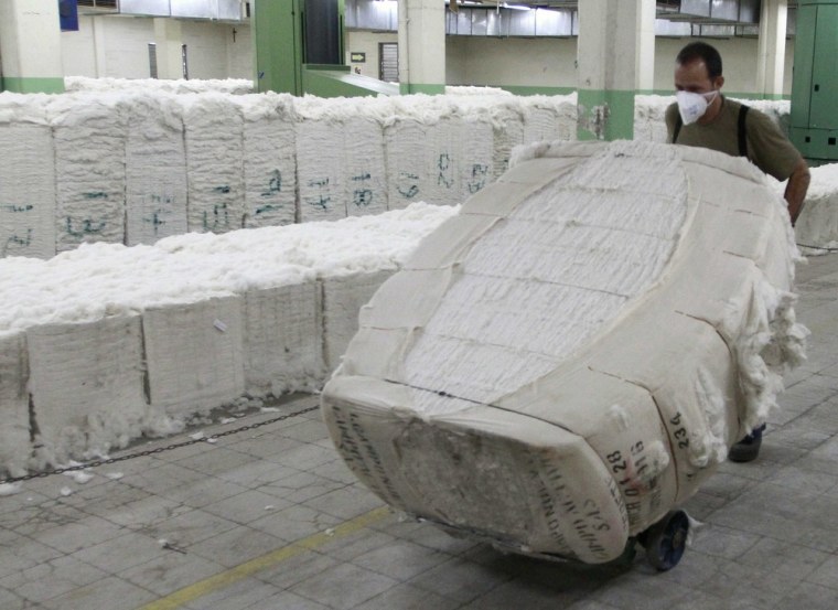 An employee pushes bundles of cotton inside a workshop of a textile factory.