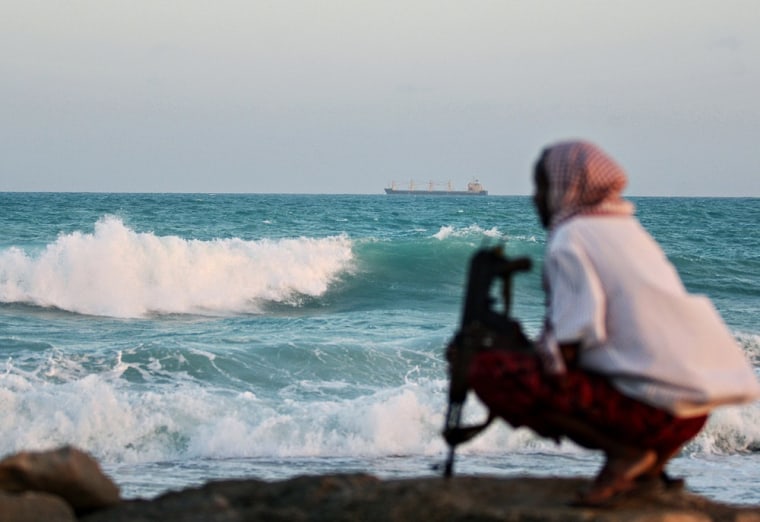 An armed Somali pirate keeps vigil on the coastline near Hobyo, northeastern Somalia, in January, 2010.