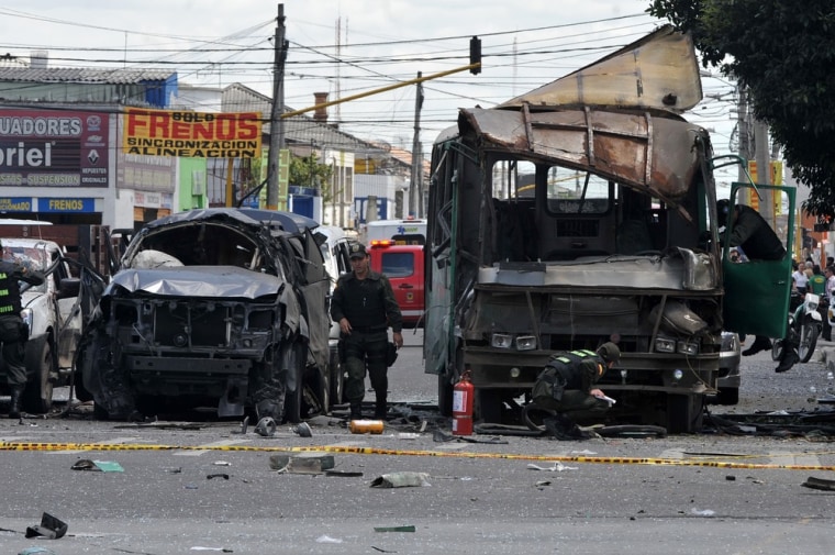 Police officers inspect the remains of vehicles on May 15, 2012 after an explosion ripped through a crowded area of Bogota injuring at least 10 people according to the mayor's office. Witnesses said the blast appeared to have been from a bomb placed on a public bus, but officials could not immediately confirm the cause.