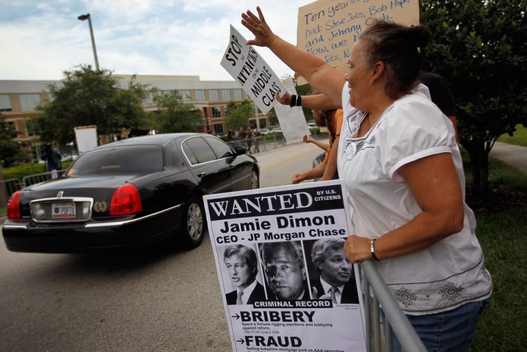 Protesters watch as cars leave outside the building where a JPMorgan Chase shareholders meeting was taking place on May 15, 2012 in Tampa, Fla.