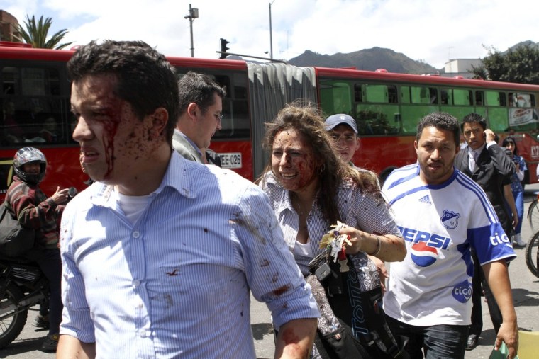 Injured people, with blood on their faces, walk at the scene of an explosion in a central avenue in Bogota. A bomb attack in a commercial district of Colombia's capital Bogota killed two people on Tuesday and injured a former interior minister who was the target, President Juan Manuel Santos said.