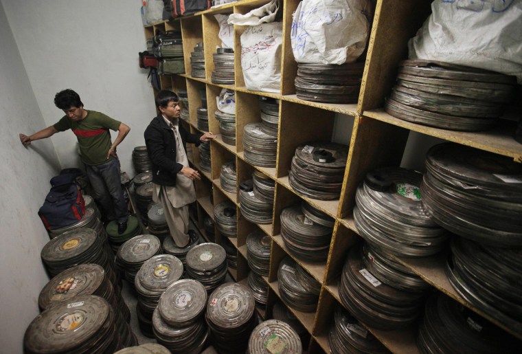 Employees of Ariana Cinema stand on film cans as they work inside a storage room in Kabul on May 3.