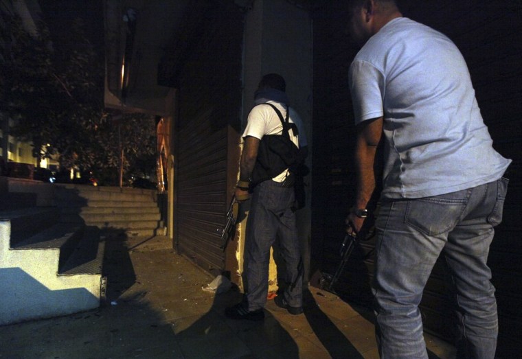 Anti-Syrian gunmen seek cover during deadly overnight clashes in Beirut, Lebanon, early on Monday.