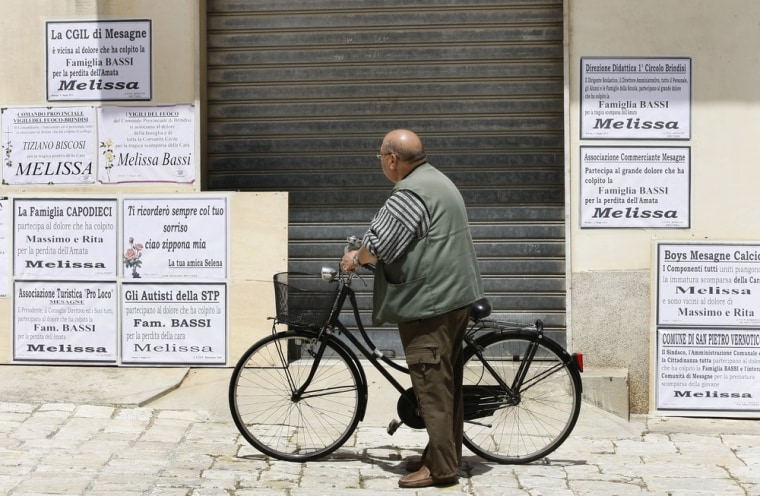 A man rides pauses to read signs outside a closed shop prior the funeral service of Melissa Bassi on May 21, in Mesagne, near Brindisi. Bassi, a fashion student, died on May 19 when a homemade bomb exploded at a vocational school just as she and fellow pupils were arriving for morning classes. Five other students were injured in the blast.