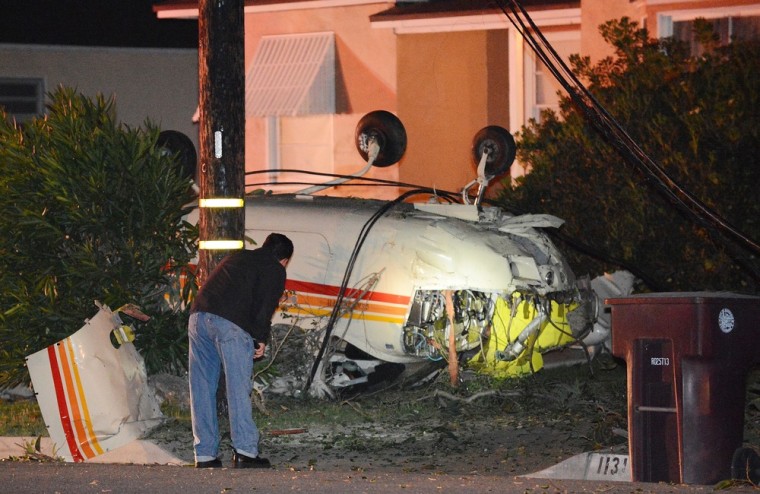 An investigator shines a flashlight on a single-engine plane which crashed in the front yard of a home in Glendale, California on May 21, 2012.