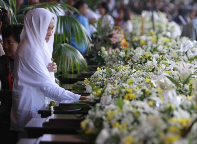 A woman places a hand on the coffin of one of the victims of the Sukhoi crash during a ceremony in Jakarta on May 23, 2012.