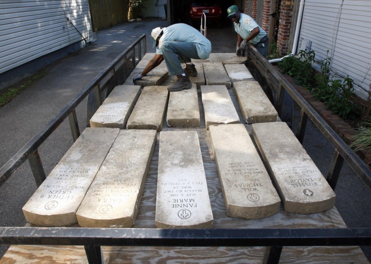 Al Williams, left, and Calvin Jackson remove tombstones that came from the Memphis National Cemetery from the Midtown back yard of Jason Blackburn in Memphis on Tuesday May 23, 2012.