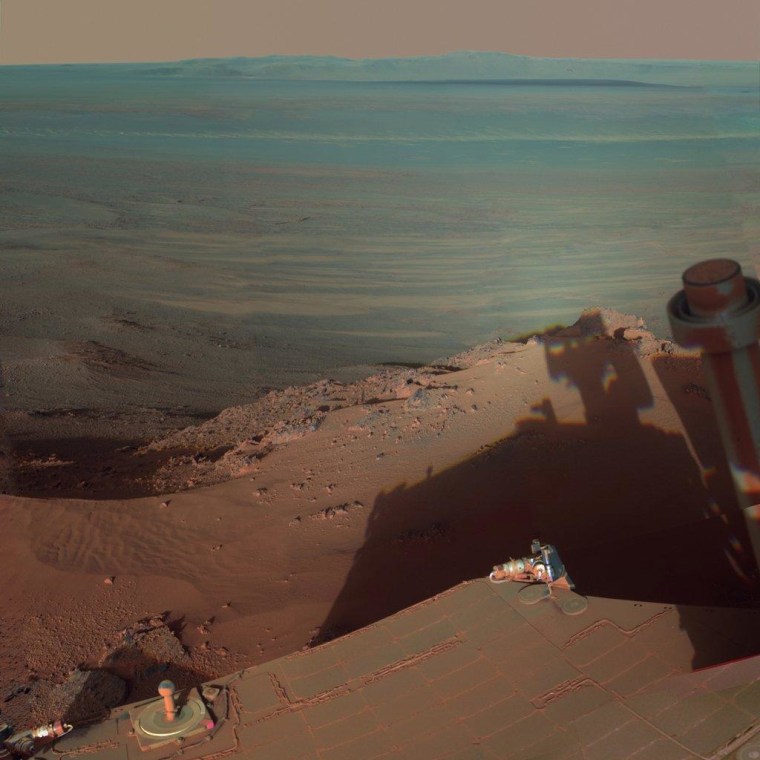 NASA's Opportunity rover catches its own late-afternoon shadow in a view looking eastward across Endeavour Crater on Mars. Endeavour measures 14 miles across, encompassing a crater with about as much area as the city of Seattle. The colors in this picture have been tweaked to exaggerate surface differences.