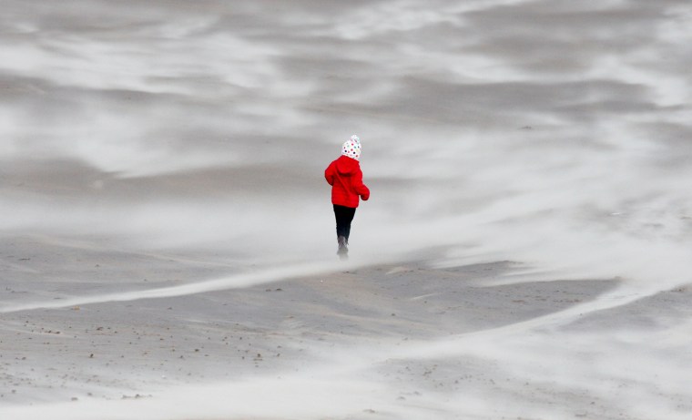 A child walks along the beach as the sand is blown around in the high winds in Seaburn, England, Jan. 3, 2012.