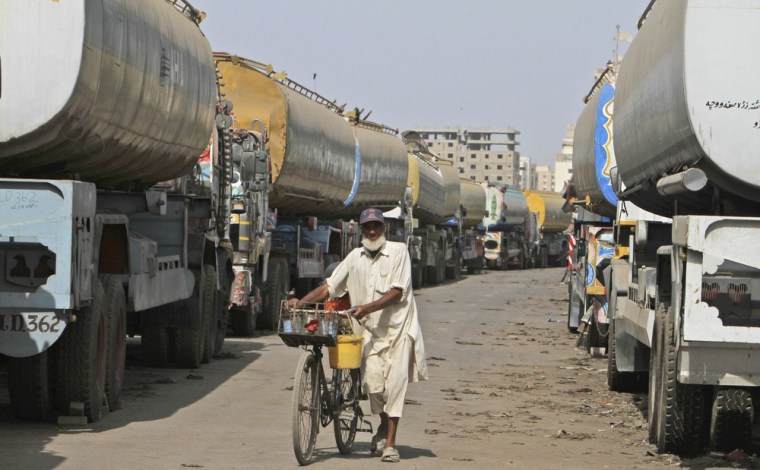 A Pakistani man selling cold drinks pushes his bicycle between oil tankers, which were used to transport NATO fuel supplies to Afghanistan, in a compound in Karachi.