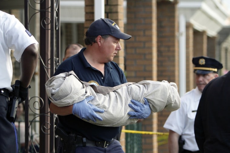 A crime scene unit member carries a body from a home in Northeast Philadelphia on Thursday after toddler twins were found dead.