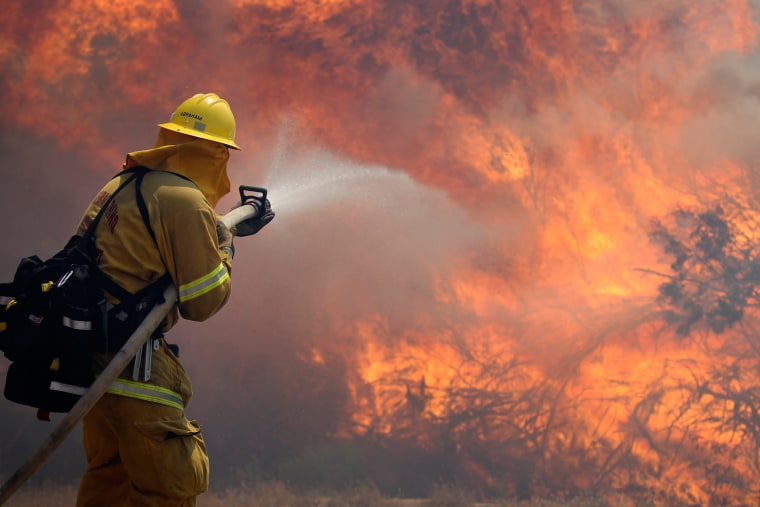 Firefighter Scott Abraham, of the San Bernardino County Fire Department, sprays water as his crew tries to keep the fire from crossing a San Diego County road Friday, May 25, 2012, near Julian, Calif.