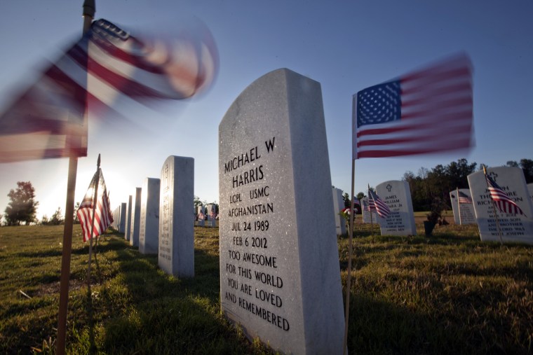 American flags wave near the grave of Marine Lance Cpl. Michael Harris as the the sun rises over Georgia National Cemetery on Memorial Day, May 28, in Canton, Ga. Harris died Feb. 6, 2012.