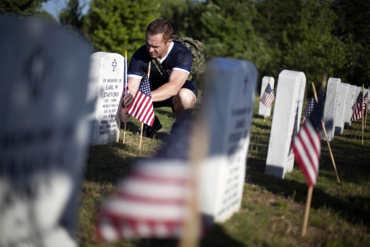 Retired U.S. Marine Sgt. Chad Casey, of Canton, Ga., places American flags at the graves at Georgia National Cemetery, Monday, May 28, 2012, in Canton, Ga.