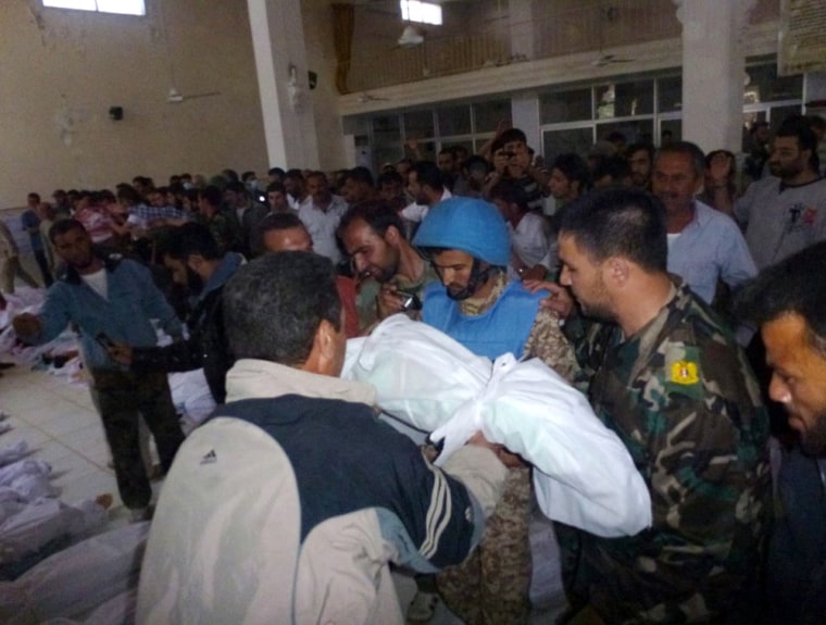 A resident of Houla shows a body to a UN observer as they stand near the bodies of people whom anti-government protesters say were killed by government security forces on Friday.