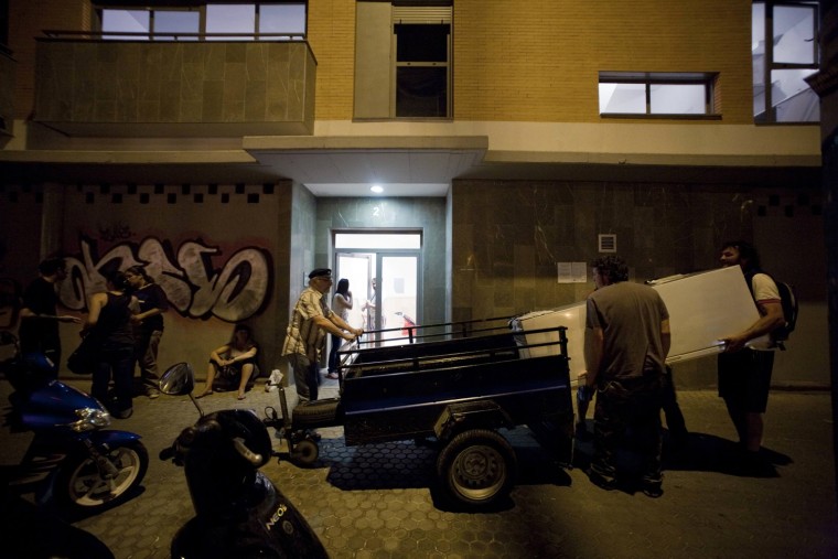 Men carry a fridge into a building that has been occupied in Seville, May 24. More than 30 struggling families are occupying an apartment in Seville in southern Spain that has been empty since it was finished three years ago. The building is one of hundreds of thousands of ghost constructions gathering dust all over Spain that banks and property developers are unable to sell. Most of the occupiers of the flats, which have brand-new wooden floors with sparkling double glazing, have been thrown out of their own homes by landlords or bailiffs after they defaulted on their mortgage or could not pay the rent.