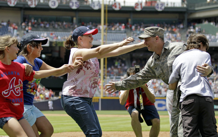 U.S Air Force Master Sgt. David Sims, center right, of Centerville, Ga., is embraced by his wife Robin, and children, Bree Anna, 10, from left, Brittney, 13, and Dustin, 12, after surprising them from his deployment in Afghanistan during the fifth inning of a baseball game between the Atlanta Braves and the St. Louis Cardinals Monday, May 28, in Atlanta.
