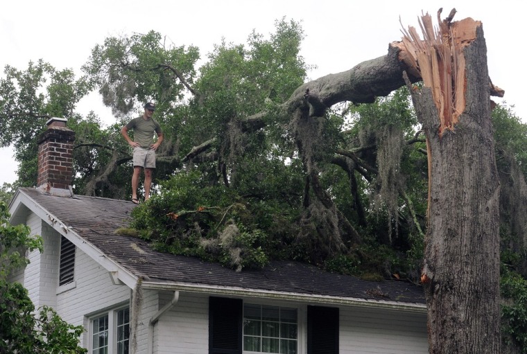 Wes Akers inspects damage on a home in Avondale, Fla., caused by a downed tree in the aftermath of Tropical Storm Beryl.