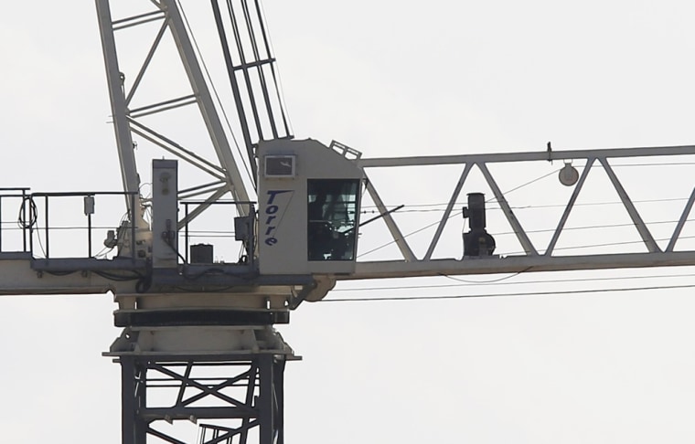A robbery suspect sits in the cab of a construction crane on the SMU campus after climbing the crane in a standoff with police in Dallas, Texas May 28.