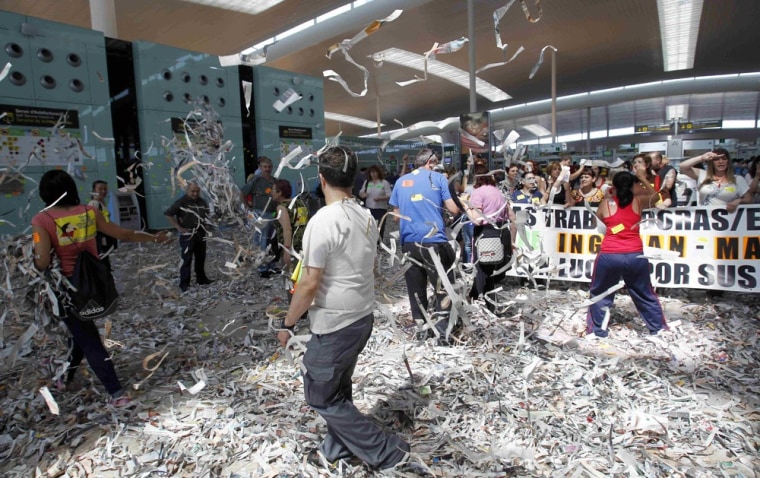 Cleaning staff workers toss pieces of papers during a protest at Barcelona's airport on Tuesday. Cleaning staff working for a company who have a contract with the airport demonstrated against pay and benefits cuts made by their employer.