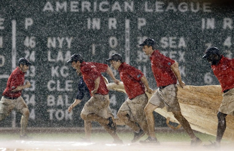 Grounds crew members quickly pull the tarp onto the field during a heavy rain shower in the eighth inning of a baseball game between the Boston Red Sox and the Detroit Tigers at Fenway Park in Boston on May 29, 2012.