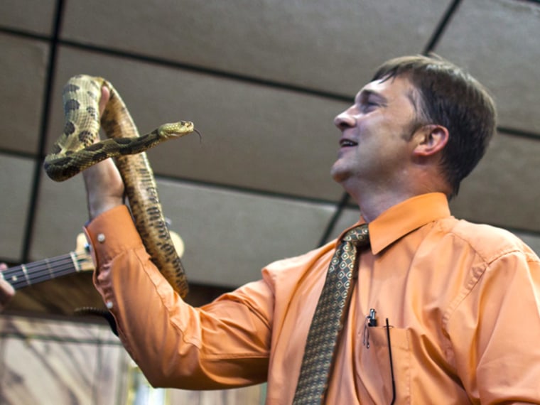Pastor Mack Wolford handles a timber rattlesnake during a service at the Church of the Lord Jesus in Jolo, W.Va., on Sept. 3.
