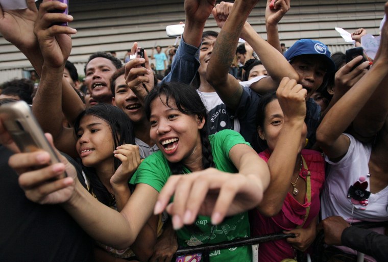Myanmar migrant workers take pictures with their mobile phones when Myanmar opposition leader Aung San Suu Kyi leaves a center following her visit in Samut Sakhon Province, Thailand on May 31.