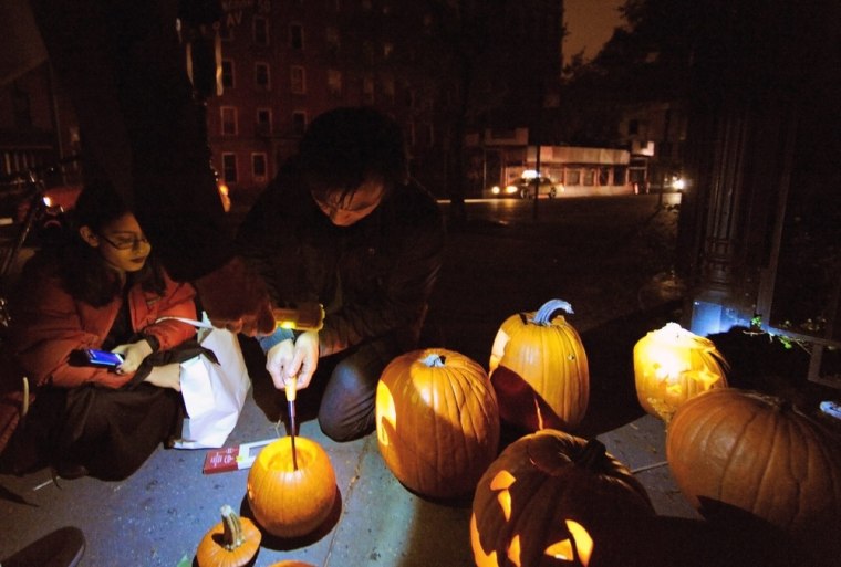 New York City residents light jack-o'-lanterns made from cut out pumpkins on Hudson Street in lower Manhattan, October 31, 2012. Hurricane Sandy knocked out power to much of lower Manhattan and has forced many residents to seek shelter in other parts of the city.