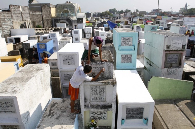 A boy darkens the inscription of a tombstone of a deceased relative during the commemoration of All Saints Day in Navotas City, Metro Manila on Nov. 1.