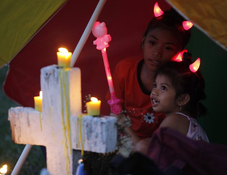 Children play beside a tombstone as their family visit deceased relatives at Heroe's cemetery to remember their departed loved ones on All Saints Day in in Taguig City in Metro Manila.