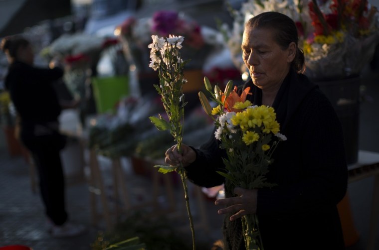 A woman prepares flowers to be sold at a cemetery during All Saints Day, a Catholic holiday to reflect on the saints and deceased relatives in Barcelona, Spain.