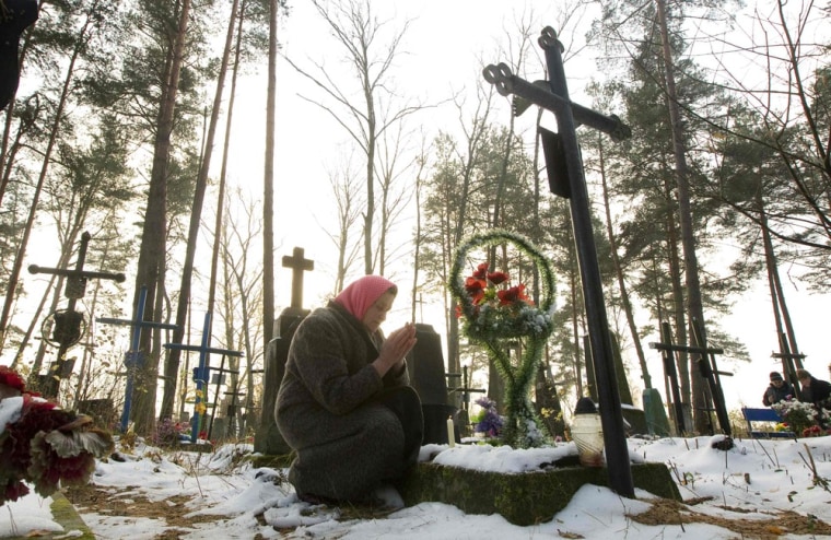 An elderly woman prays near a grave at a cemetery in the village of Ivenets, 31 miles southwest of Minsk, on Nov. 1. Catholics in Belarus marked All Saints Day by visiting the graves of their relatives and friends.