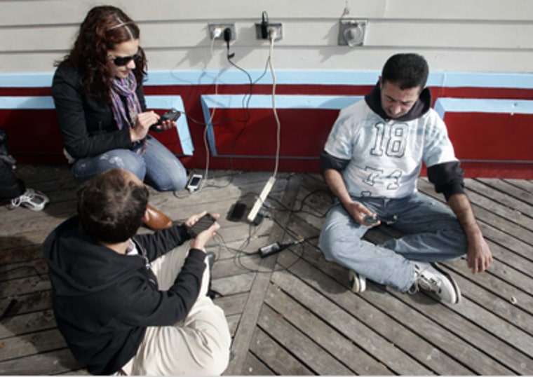 Atlantic City residents who are without power in their homes, recharge their cellphones and those of friends from an outdoor electrical outlet at one one of the boardwalk casinos in Atlantic City.