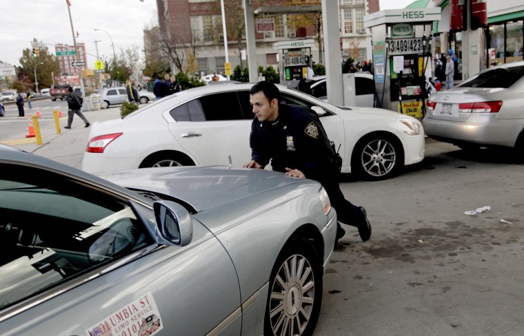 A police officer moves a car that is out of gas, trying to position it so it can fill up, at a gas station in Brooklyn, N.Y. on Nov. 2.