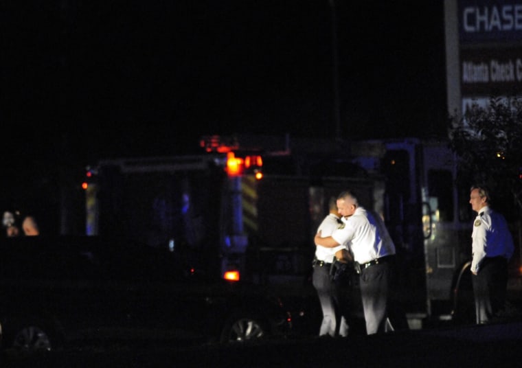 Law enforcement personnel embrace early Sunday as others investigate the scene of an Atlanta Police Department helicopter crash that killed two officers aboard.