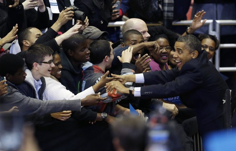 President Barack Obama reaches over to greet supporters before speaking at in Cincinnati.