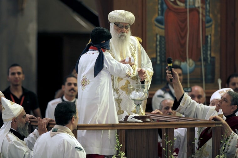 A blindfolded boy draws the name of the next pope from a crystal chalice next to acting Coptic Pope Pachomios, center, during the papal election ceremony at the Coptic Cathedral in Cairo on Nov. 4, 2012.